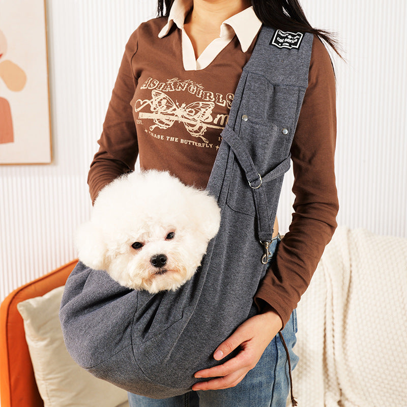 Grey pet sling shoulder bag carrying a small dog