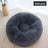 Dog curled up in a dark grey and white round bed