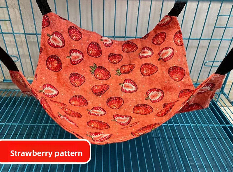 Cat lounging in a strawberry pattern cage hammock