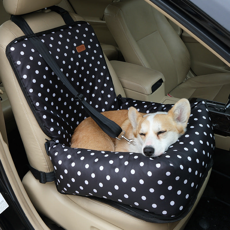Small dog travelling in a grey plaid car seat bed