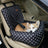 Small dog travelling in a grey plaid car seat bed