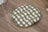 Cat sleeping in a green woven rattan bed with fish pattern pad