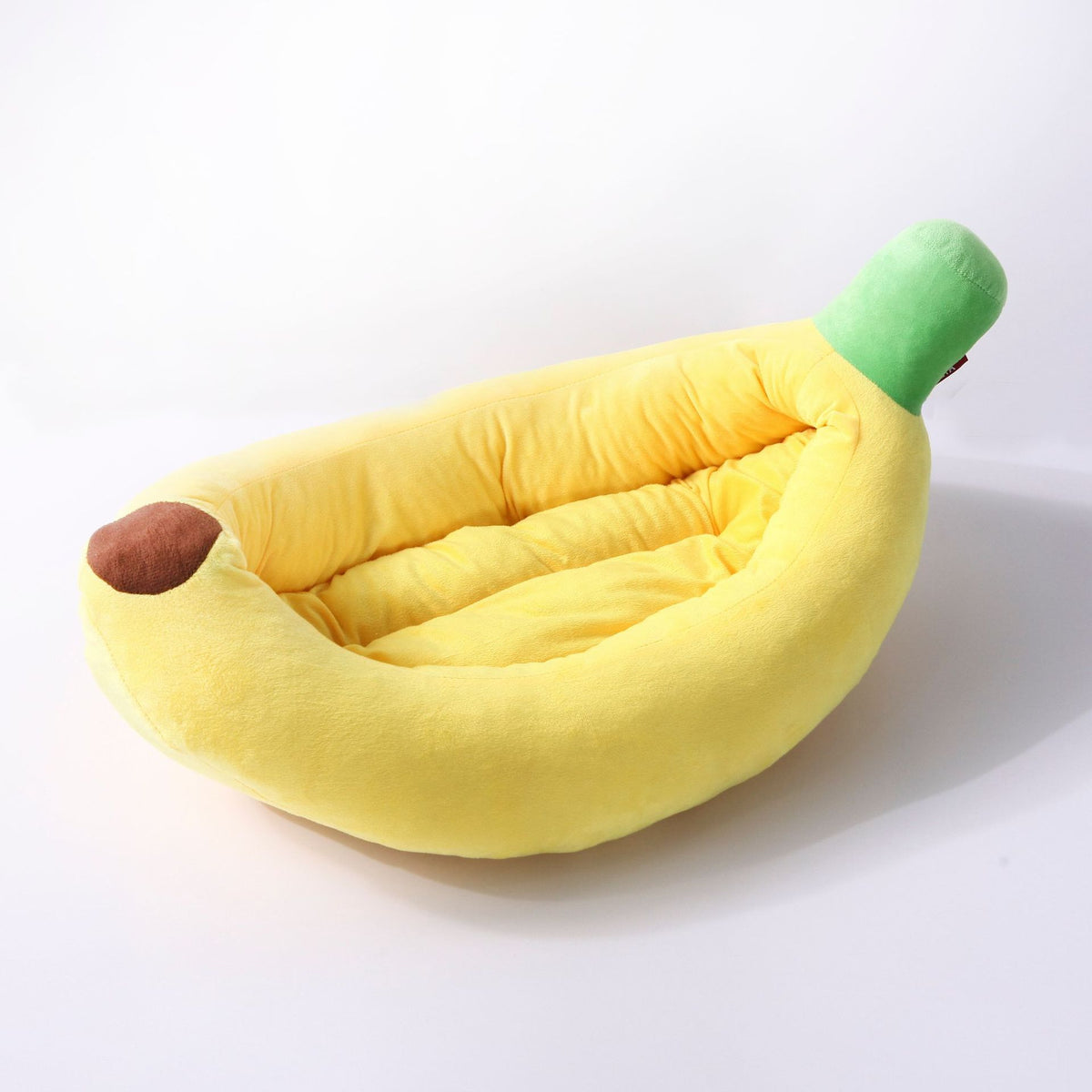 Kitten sleeping in a yellow banana cat bed with heart bone pillow