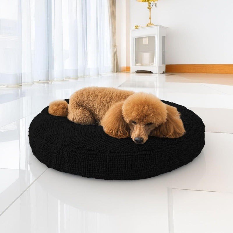 Small dog curled up in a black chenille donut bed