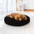 Small dog curled up in a black chenille donut bed