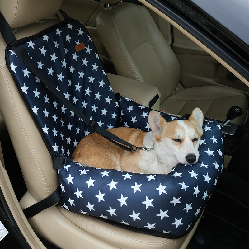 Small dog travelling in a grey plaid car seat bed