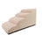 Beige two-step dog steps placed beside a sofa