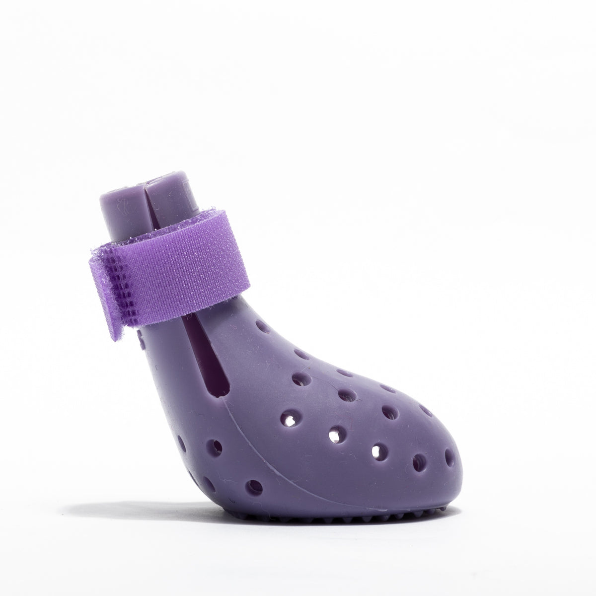 Small dog wearing bright silicone rain boots on a wet pavement