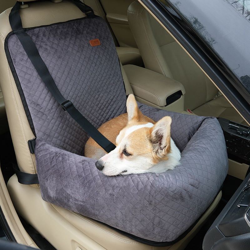 Small dog travelling in a grey plaid car seat bed