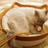 Rattan woven cat nest with ball toy and cream pad, view 1